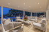 Covered outdoor lounge with modern sofas and pool view at dusk in a luxury St Barts villa rental.