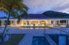 Evening view of luxury St Barts villa with pool terrace and illuminated interiors surrounded by tropical hills.