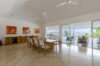 Bright dining room in St Barts villa with marble floors, contemporary art, and ocean views through sliding glass doors.