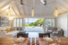 Open-concept living and dining area in a St Barts villa with ocean views through wide terrace doors.