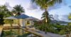 Luxury villa in St Barts with palm-lined pool terrace, shaded loungers, and ocean views at dusk.