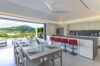 Open-plan kitchen and dining area in a St Barts villa with hillside views, set table, and bar seating in modern design.
