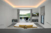Bedroom in a St Barts villa with terrace access, hillside views, and lounge chairs framed by soft natural light.