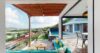 Shaded terrace with turquoise seating, wooden deck, and hillside views beside a private pool in a St Barts villa rental.