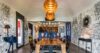 Artistic dining room in a St Barts villa with long wooden table, bold patterned walls, and statement pendant lighting.