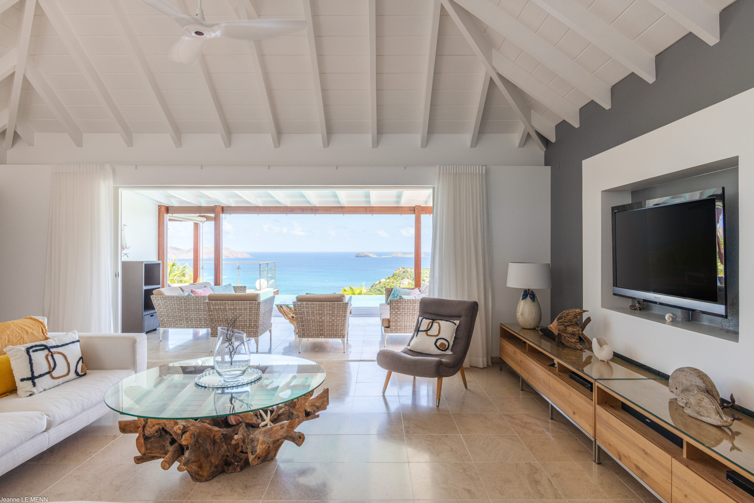 Bright living room in a St Barts villa with driftwood coffee table, modern décor, and terrace views of the ocean.