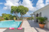 Sunny pool terrace with ocean view, tropical plants, and loungers in a private St Barts villa rental.