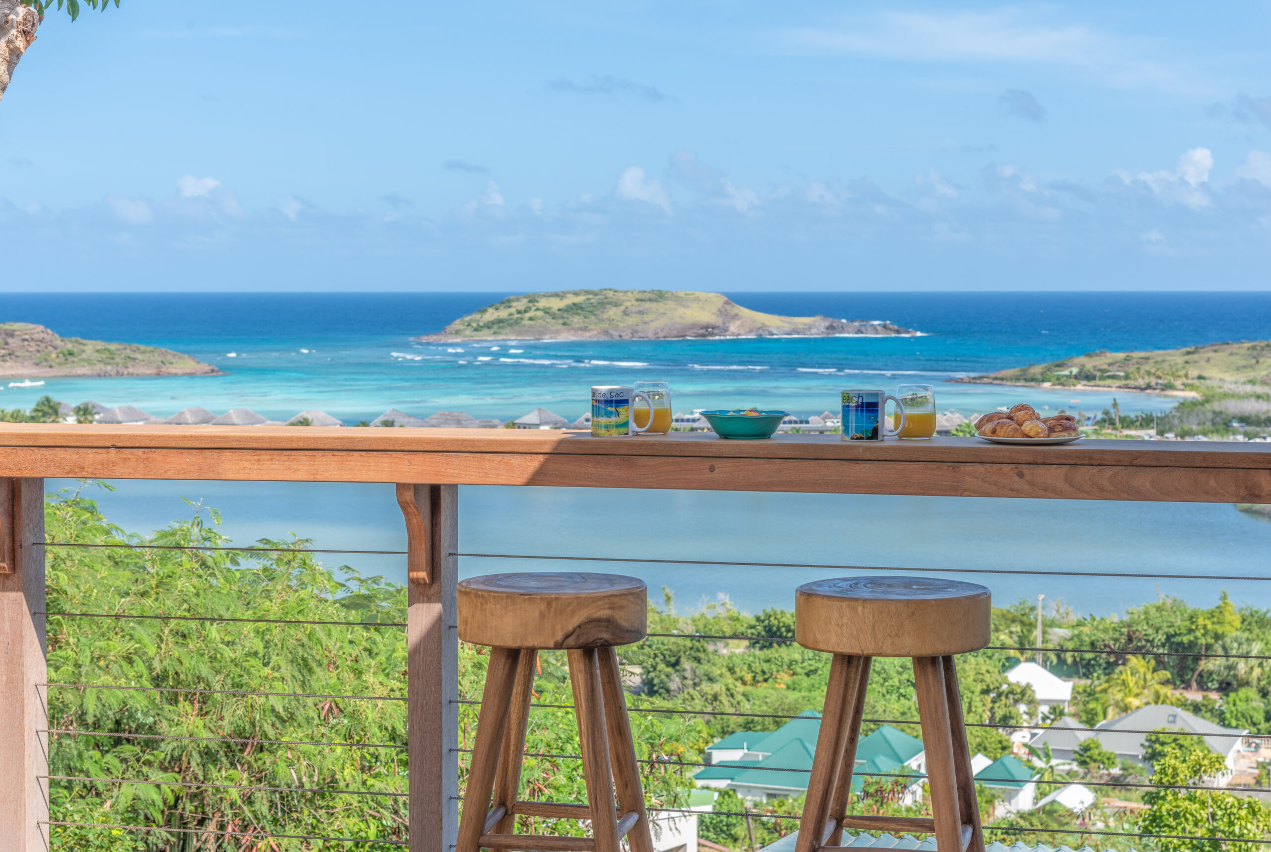 Ocean-view breakfast bar with wooden stools overlooking turquoise waters in a St Barts villa rental.