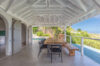 Shaded outdoor dining area with rustic wooden table and hillside views in a private St Barts villa rental.