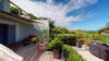 Sunny villa terrace with potted plants, lounge seating, and lush greenery overlooking the hills of St Bart.