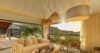 Sunlit living room in St Barts villa with natural decor, open terrace, and hillside views at sunset