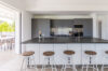 Modern kitchen with large black island, bar stools, and open terrace access in a luxury St Barts villa rental.