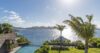 Clifftop pool at St Barts villa with palm trees, ocean views, and lush garden