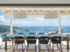 Outdoor dining terrace in a St Barts villa with woven chairs, long table, and sweeping views over the Caribbean Sea.