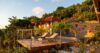 Sunset terrace at a St Barts villa with loungers, palm trees, and hillside gardens bathed in golden light.