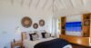 Stylish bedroom in a St Barts villa with vaulted ceiling, natural wood furnishings, and wall-mounted TV.