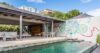 Poolside lounge in a St Barts villa with colorful mural wall, shaded terrace, and open-air dining area.