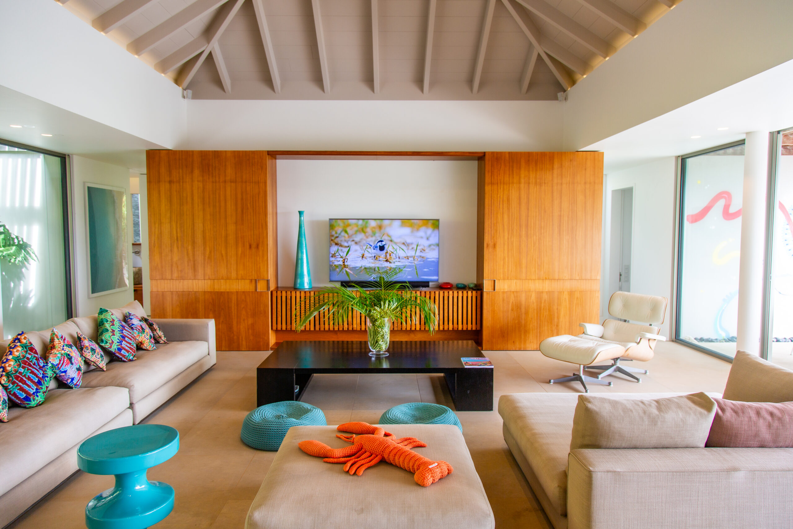 a cozy living room with a large flat-screen television built into a wooden cabinet, a low black coffee table, and comfortable couches with colorful throw pillows