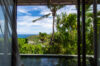 a bedroom with a view to a private plunge pool, lush vegetation, and the ocean in the distance