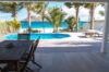 Beachfront St Barts villa with shaded dining terrace, private pool, and turquoise Caribbean Sea views framed by palm trees