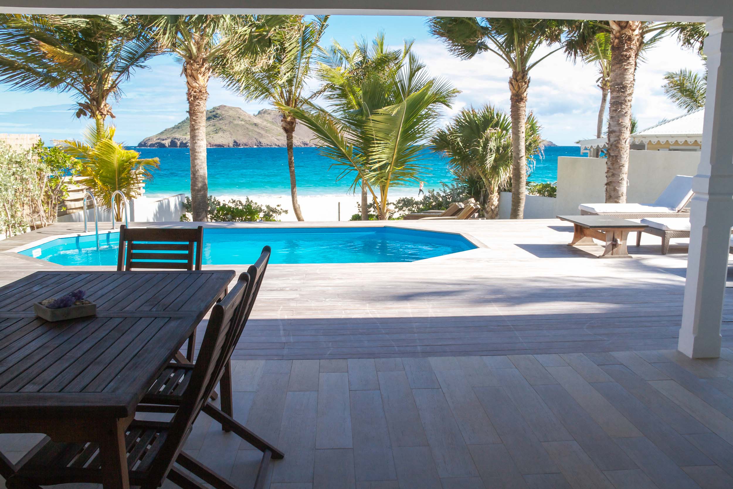 Beachfront St Barts villa with shaded dining terrace, private pool, and turquoise Caribbean Sea views framed by palm trees