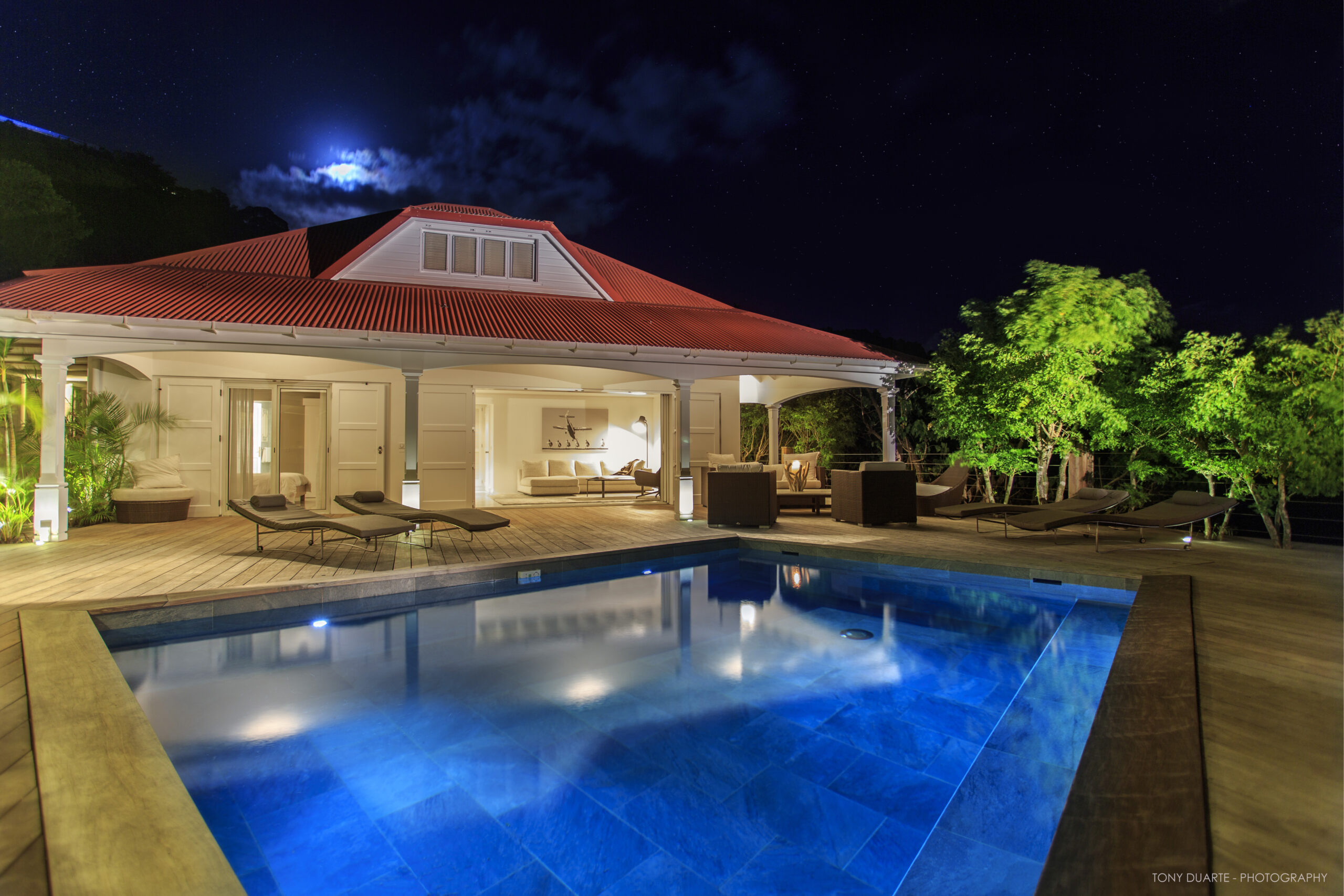 St Barts villa infinity pool illuminated at night with serene ocean backdrop.
