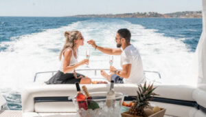 Couple enjoying champagne and snacks on a private yacht charter with ocean views.