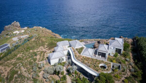 Aerial view of a luxury villa perched on a cliffside in St. Barts, featuring modern architecture and panoramic ocean views.